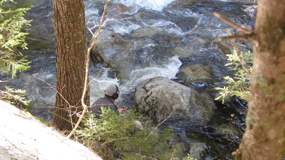 photo of ben recording water sounds in the field with a microphone and a portable recorder.