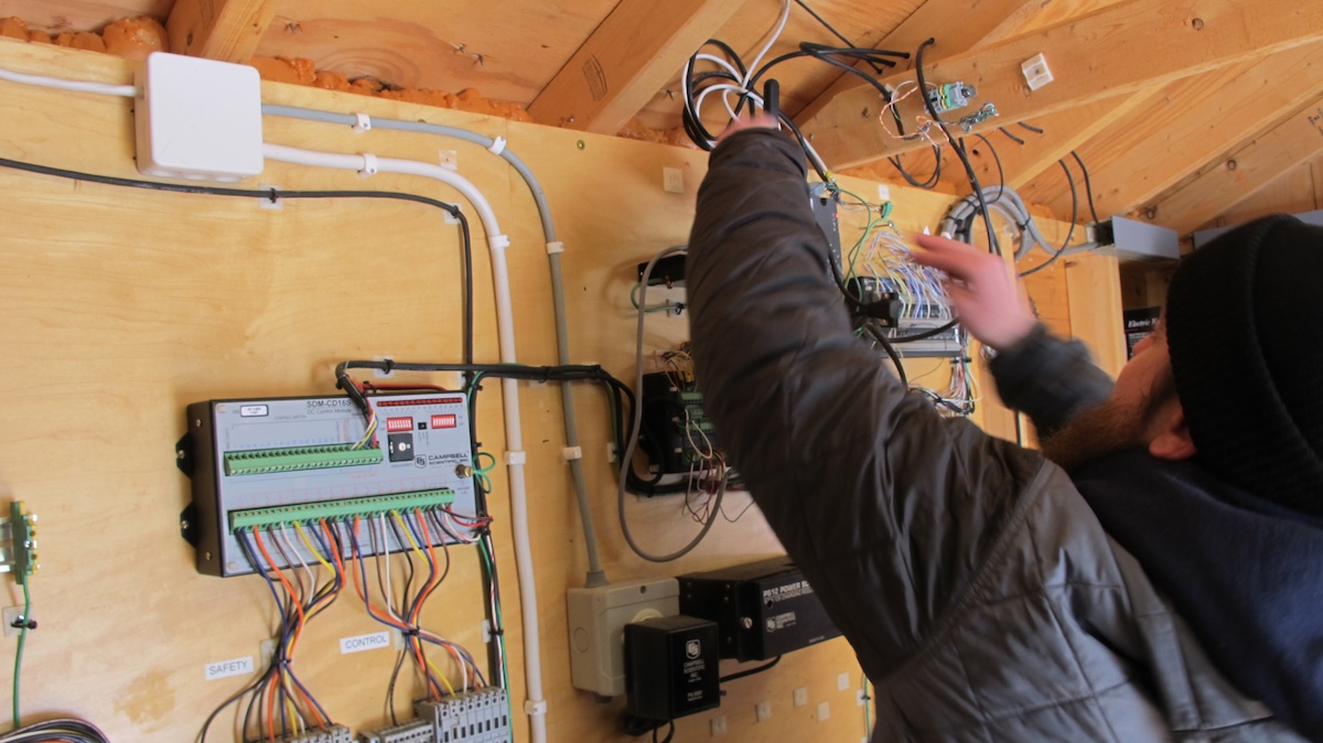 photo of environmental sensors and a field technician inside of a shed